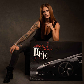 Frau mit tätowiertem Arm sitzt neben Motivationsbild mit Sportwagen und Text Step up your life