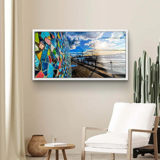 Modernes Wandbild mit bunter Mosaik-Fassade und Seeblick unter blauem Himmel im Wohnzimmer