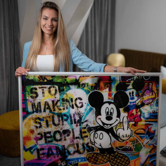 Frau hält Pop Art Wandbild mit bunter Micky Maus und Graffiti-Elementen im modernen Raum