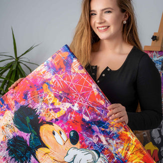 Frau hält farbenfrohes Wandbild mit Comic-Motiv im Pop Art Stil, abstrakte Micky Maus