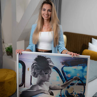 Frau hält Wandbild mit Retro-Frau im Oldtimer, modernes Wohnzimmer, Kunstfoto