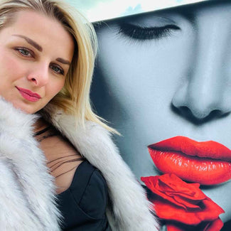 Frau mit blonden Haaren vor Wandbild in Pop Art Stil, rote Lippen und rote Rose