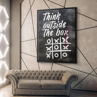 Modernes Wandbild mit Spruch 'Think outside the box' und Tic-Tac-Toe Motiv über einem Sofa
